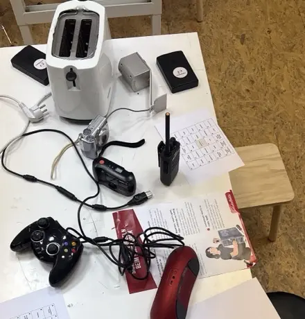Aufgeschraubter Toaster, alte Fotoapparate und ein Funkgerät auf dem Werkstatttisch