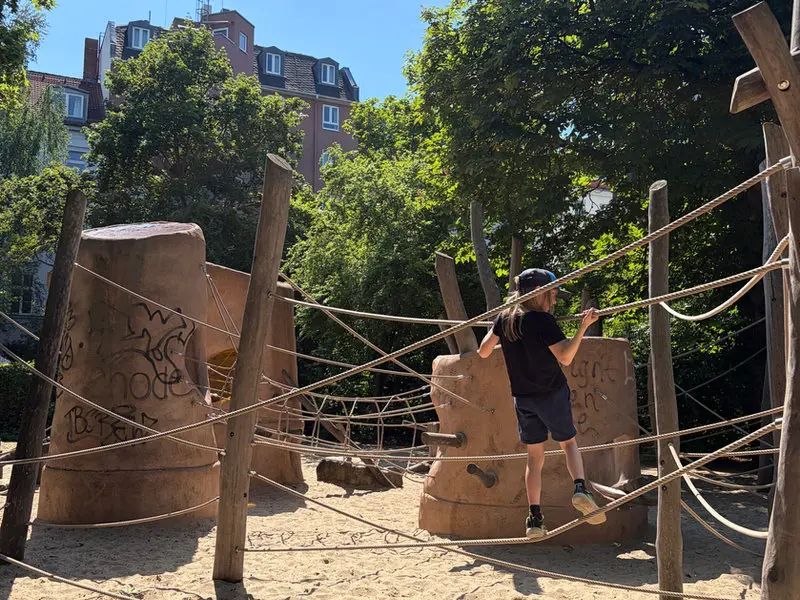 Kind klettert auf dem Spielplatz neben der Werkstatt